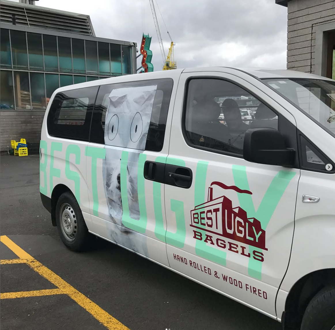 Van with 'Best Ugly Bagels' branding in a parking lot